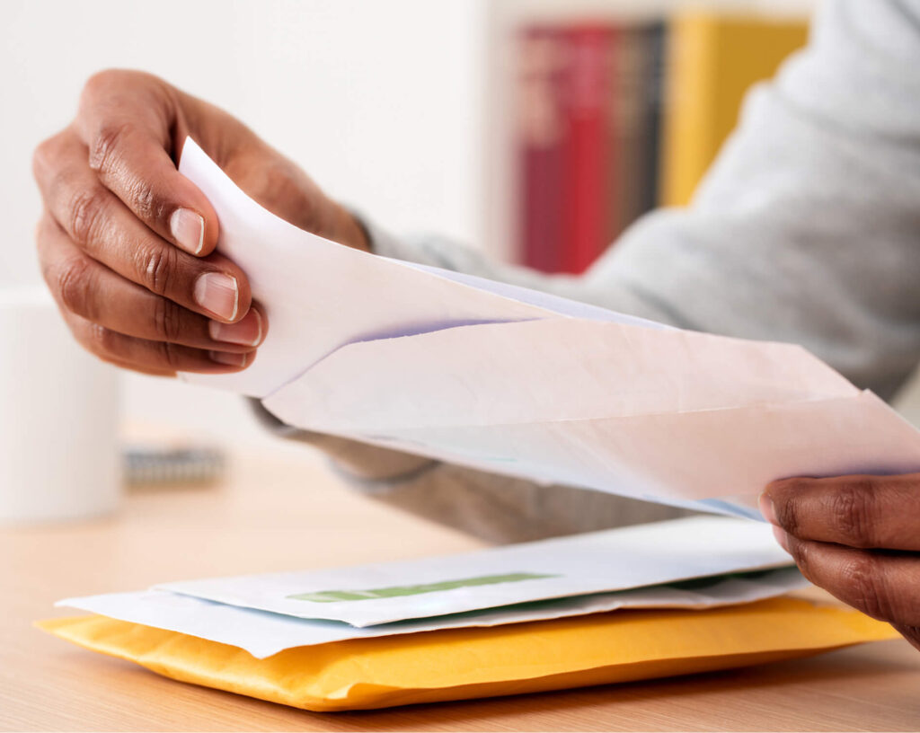 Close up of a man's hands opening a letter from a piece of mail.